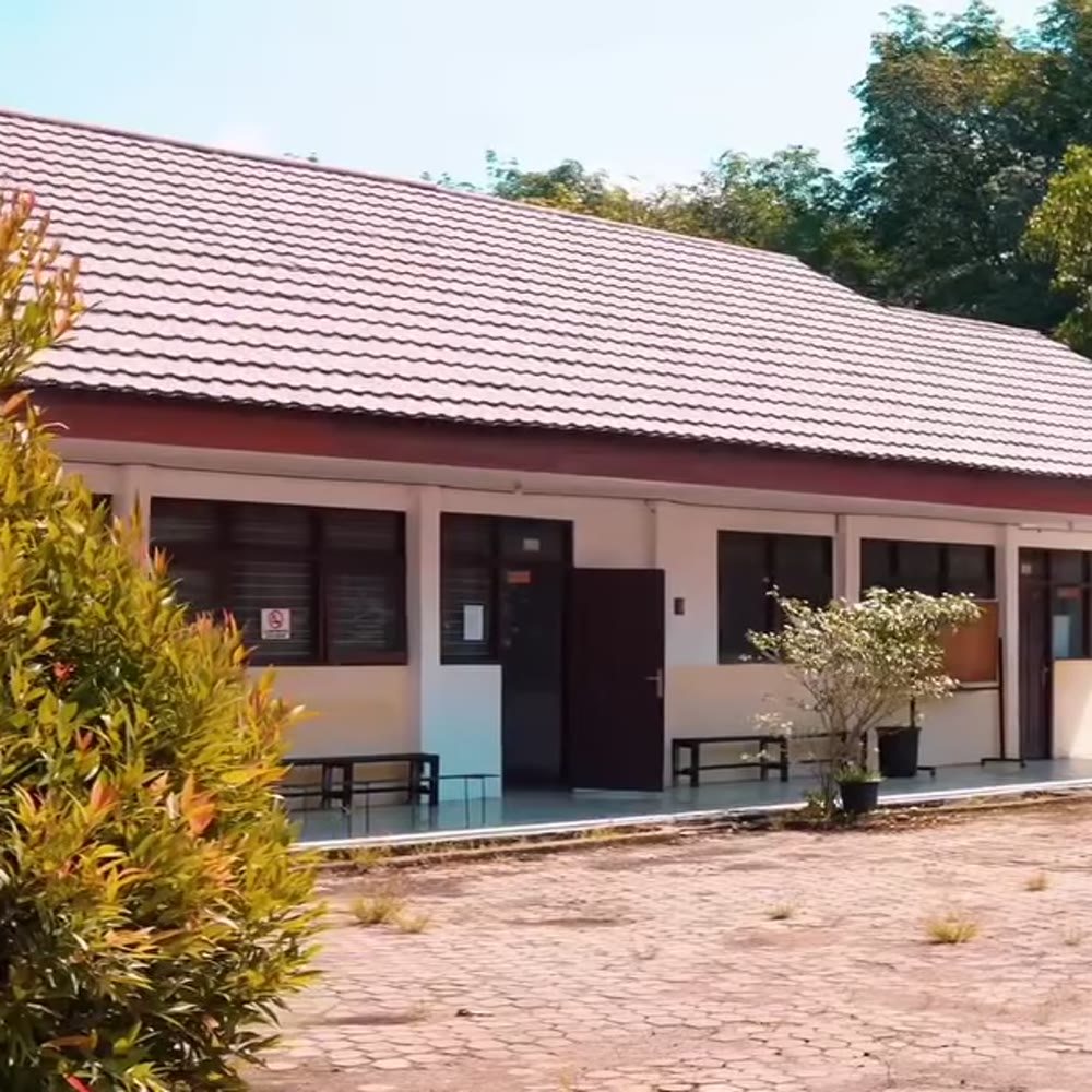 Muka gedung kampus POLTEK SSA Rantau dengan selasar beratap dan halaman di depannya